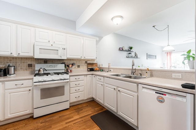 kitchen featuring white appliances, wood finished floors, a sink, decorative backsplash, and white cabinetry