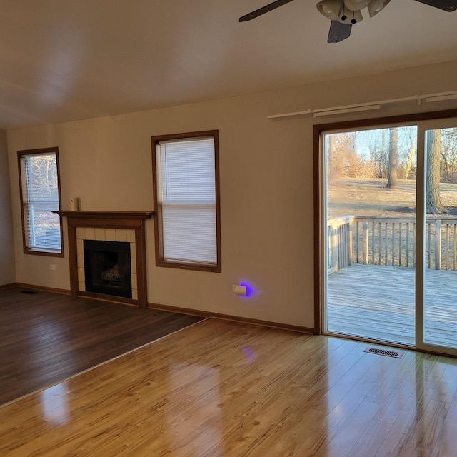 unfurnished living room with a fireplace, wood finished floors, visible vents, and baseboards