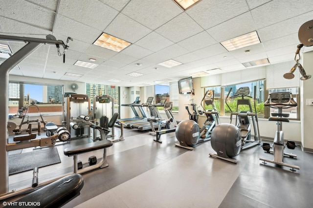 gym featuring a paneled ceiling and baseboards