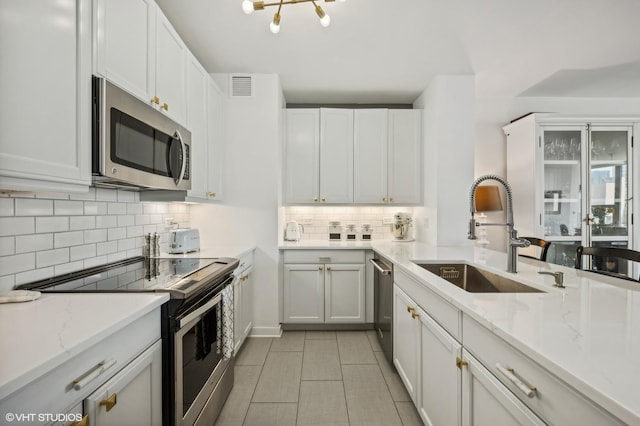 kitchen with visible vents, decorative backsplash, stainless steel appliances, white cabinetry, and a sink