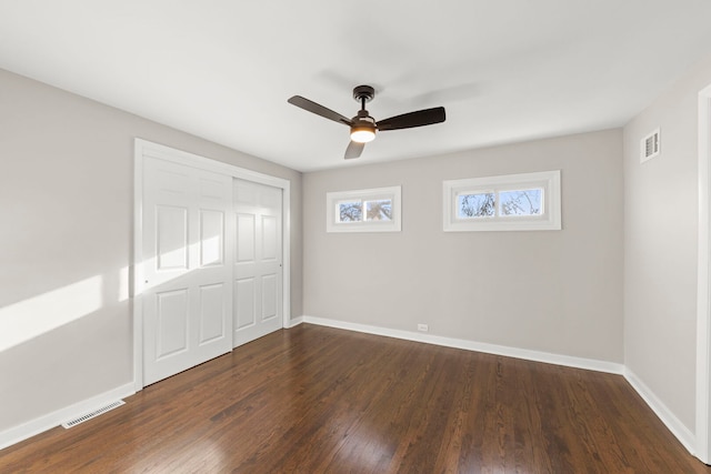 unfurnished bedroom with visible vents, baseboards, and dark wood finished floors