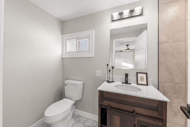 bathroom with baseboards, toilet, marble finish floor, vanity, and a ceiling fan