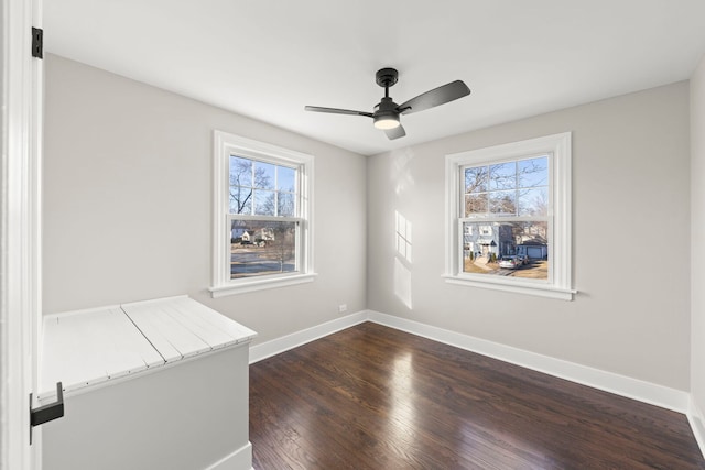 empty room with a wealth of natural light, baseboards, ceiling fan, and dark wood-style flooring