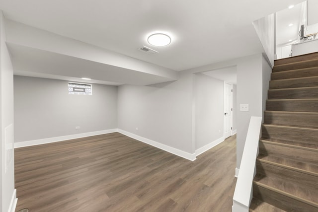 finished below grade area with dark wood finished floors, visible vents, stairs, and baseboards