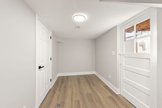 hallway featuring visible vents, light wood-type flooring, and baseboards