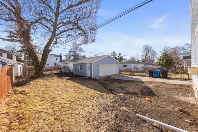 view of yard featuring a residential view, a detached garage, an outdoor structure, and fence