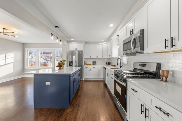 kitchen with dark wood finished floors, a sink, white cabinets, appliances with stainless steel finishes, and blue cabinets