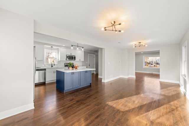 kitchen featuring a sink, open floor plan, a center island, white cabinetry, and stainless steel appliances