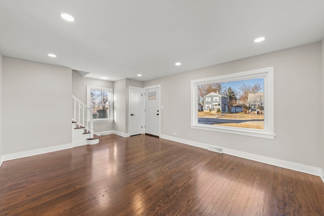 unfurnished living room with visible vents, hardwood / wood-style flooring, recessed lighting, stairway, and baseboards