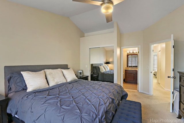 bedroom with a ceiling fan, baseboards, vaulted ceiling, light carpet, and connected bathroom