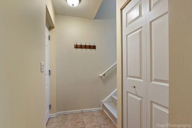 corridor featuring light tile patterned floors, stairway, and baseboards