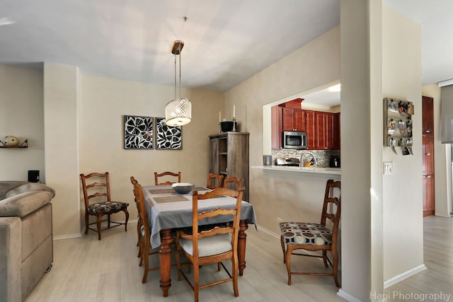 dining room featuring light wood-style flooring and baseboards