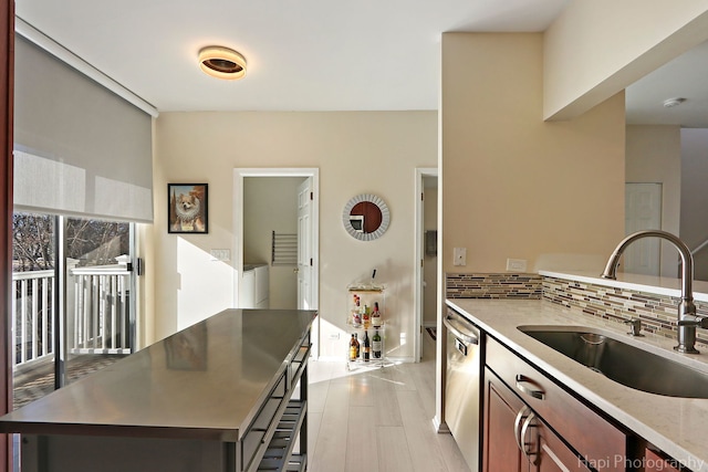 kitchen with tasteful backsplash, light wood finished floors, a sink, a center island, and stainless steel dishwasher