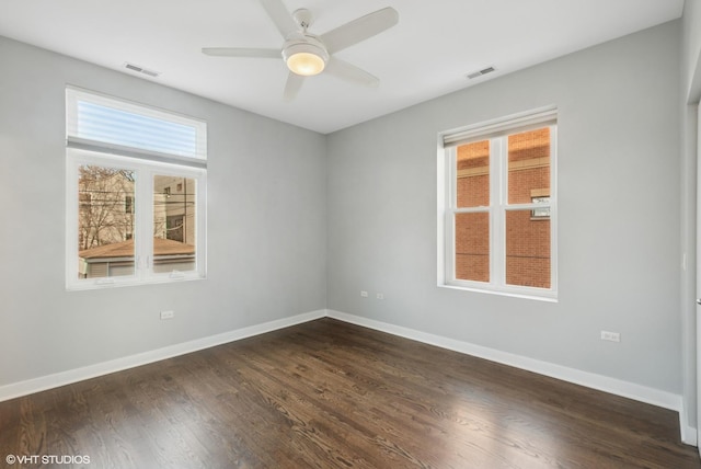 spare room featuring visible vents, baseboards, and dark wood-type flooring