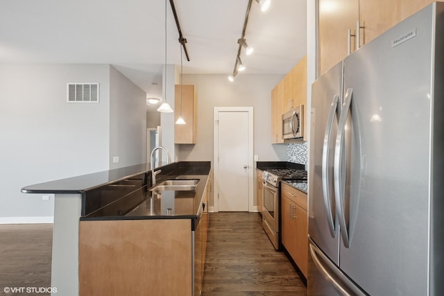 kitchen featuring visible vents, a sink, appliances with stainless steel finishes, a peninsula, and dark wood-style flooring