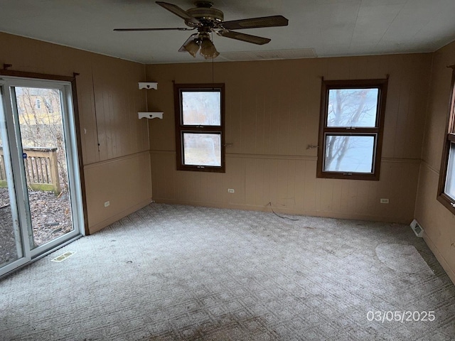 empty room with ceiling fan, visible vents, and light carpet