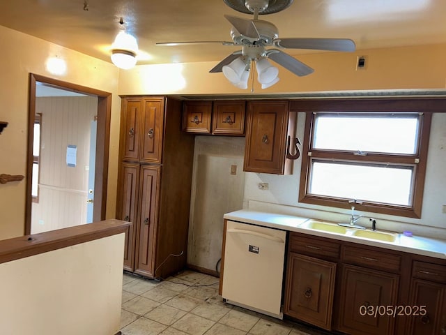 kitchen with a sink, brown cabinetry, light countertops, dishwasher, and ceiling fan