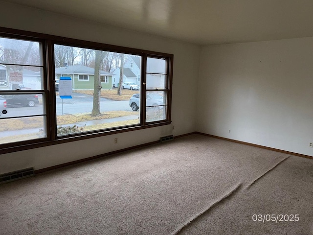 empty room featuring visible vents, baseboards, and carpet