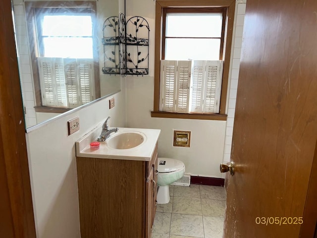 bathroom featuring baseboards, toilet, and vanity