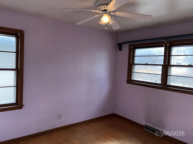 spare room with visible vents, a ceiling fan, baseboards, and wood finished floors