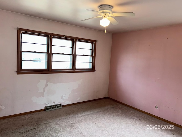 unfurnished room featuring a wealth of natural light, visible vents, baseboards, and carpet