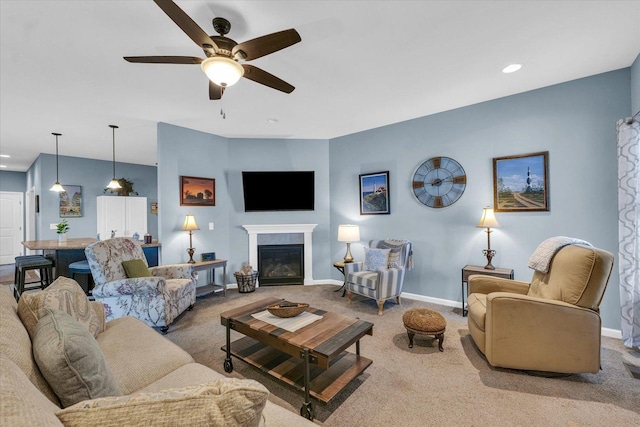 living area with ceiling fan, a tile fireplace, baseboards, and carpet