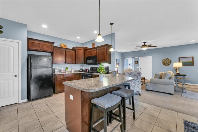 kitchen featuring light tile patterned floors, a kitchen breakfast bar, black appliances, and a peninsula