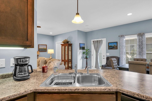 kitchen with a sink, open floor plan, recessed lighting, dark brown cabinetry, and hanging light fixtures