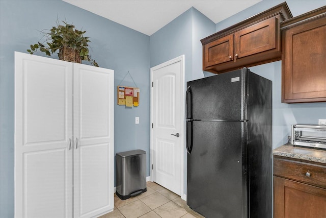 kitchen with light tile patterned floors, a toaster, and freestanding refrigerator