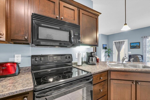 kitchen featuring black appliances, decorative light fixtures, light countertops, and a sink