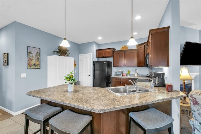 kitchen featuring a peninsula, freestanding refrigerator, a sink, light countertops, and pendant lighting