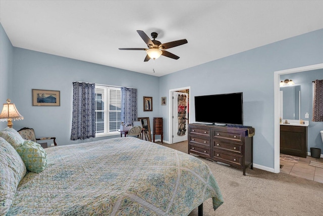 bedroom with a ceiling fan, ensuite bath, carpet floors, baseboards, and a spacious closet