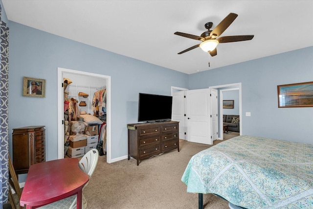 bedroom with a ceiling fan, baseboards, a closet, a walk in closet, and carpet flooring