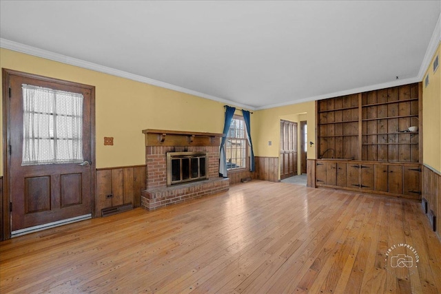 unfurnished living room featuring wainscoting, a fireplace, built in shelves, and hardwood / wood-style flooring