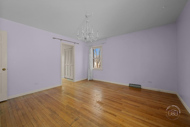 unfurnished room with baseboards, light wood-style floors, and an inviting chandelier