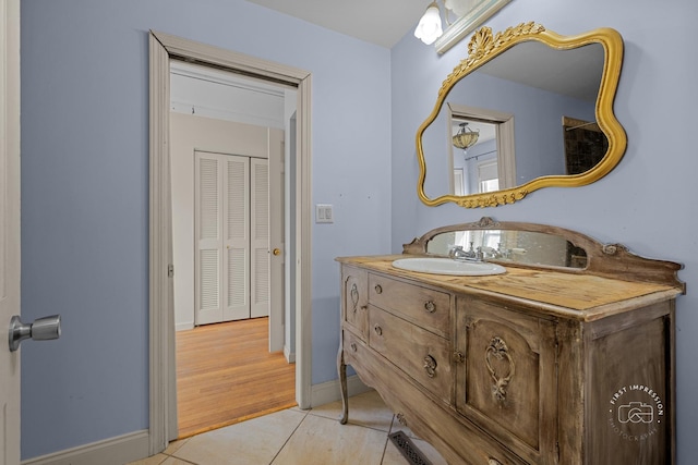 bathroom with baseboards, vanity, and tile patterned flooring