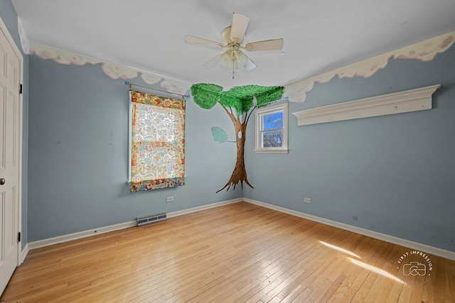 unfurnished room with visible vents, a ceiling fan, baseboards, and hardwood / wood-style flooring