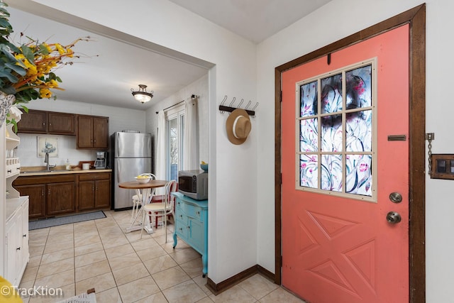 foyer entrance featuring light tile patterned flooring and baseboards