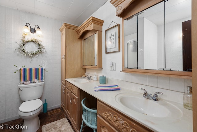 bathroom featuring tile walls, toilet, double vanity, and a sink