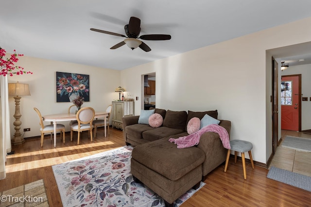 living room featuring ceiling fan, baseboards, and wood finished floors