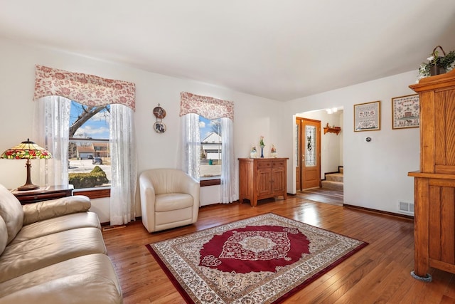 living room featuring visible vents, light wood-style flooring, stairs, and baseboards