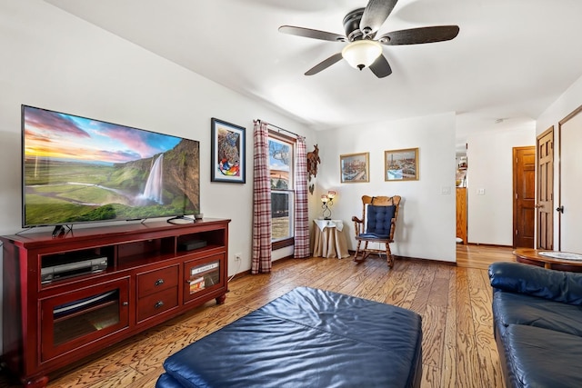 living area with light wood-type flooring, baseboards, and ceiling fan