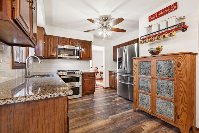 kitchen featuring backsplash, dark wood-type flooring, stainless steel appliances, a ceiling fan, and a sink