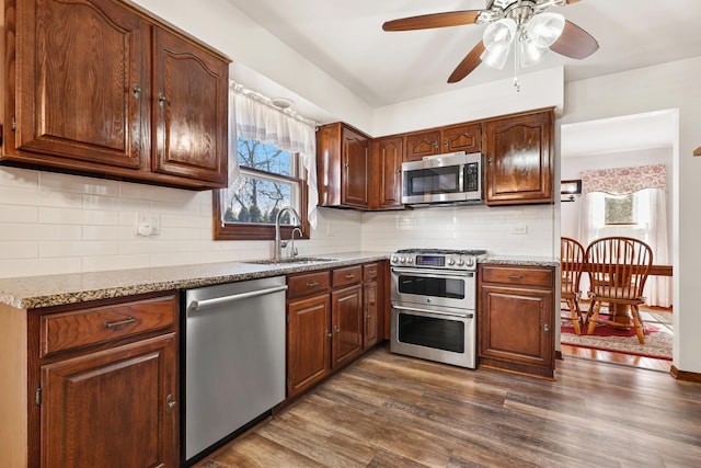 kitchen featuring a sink, tasteful backsplash, appliances with stainless steel finishes, ceiling fan, and dark wood-style flooring