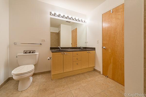 bathroom with baseboards, toilet, double vanity, tile patterned floors, and a sink