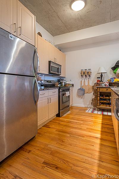 kitchen with dark countertops, appliances with stainless steel finishes, light wood-type flooring, and baseboards