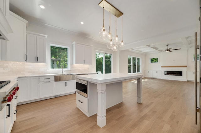 kitchen featuring light wood finished floors, decorative backsplash, a fireplace, and a center island