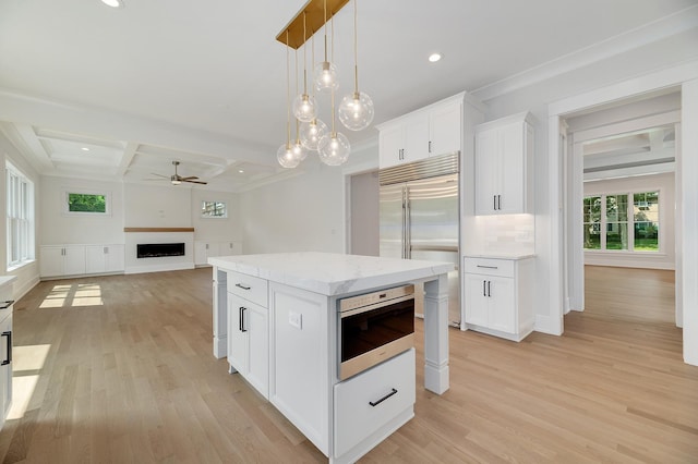 kitchen featuring light wood-type flooring, backsplash, stainless steel built in refrigerator, and a fireplace