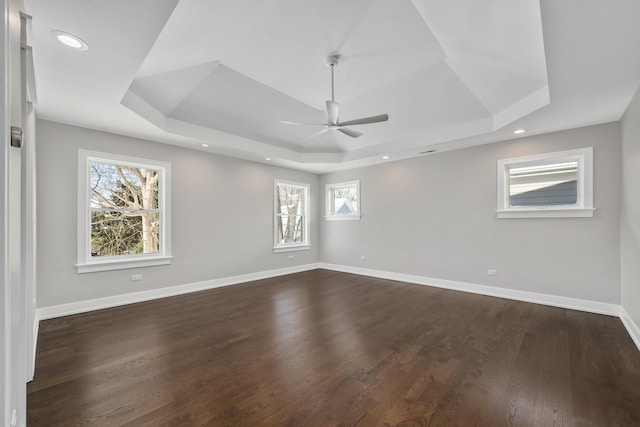 unfurnished room with dark wood-type flooring, a ceiling fan, a tray ceiling, recessed lighting, and baseboards