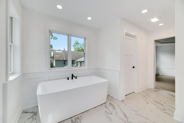 bathroom with recessed lighting, a freestanding tub, marble finish floor, and a wainscoted wall